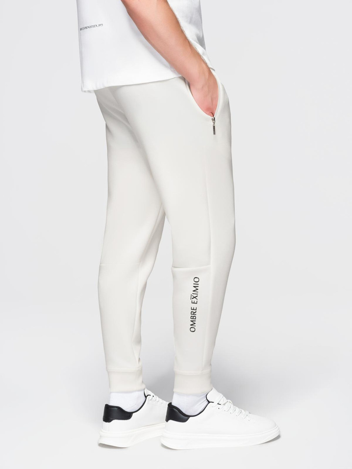 Dresowe spodnie męskie ze ściągaczami w nogawkach i gumowym nadrukiem – białe V2 OM-PASK-0223
